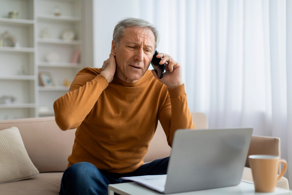 elderly man stressed with ransomware hack staring at screen calling customer support