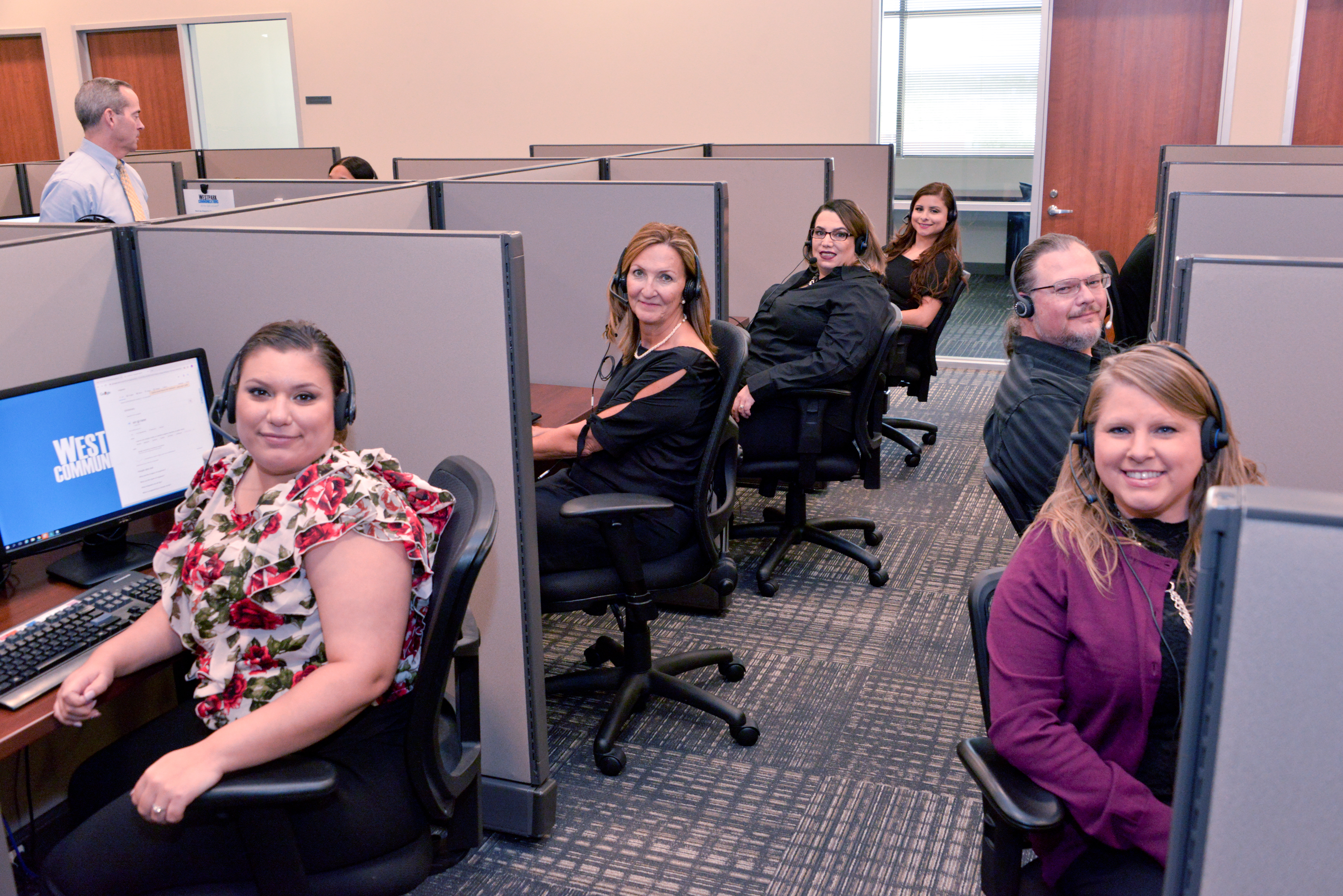 call center office with four females left and one female and male right sitting in chairs