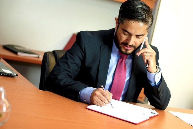 Attorney in a black suit and red tie reviewing legal documents over the phone representing mass tort intake and legal lead handling